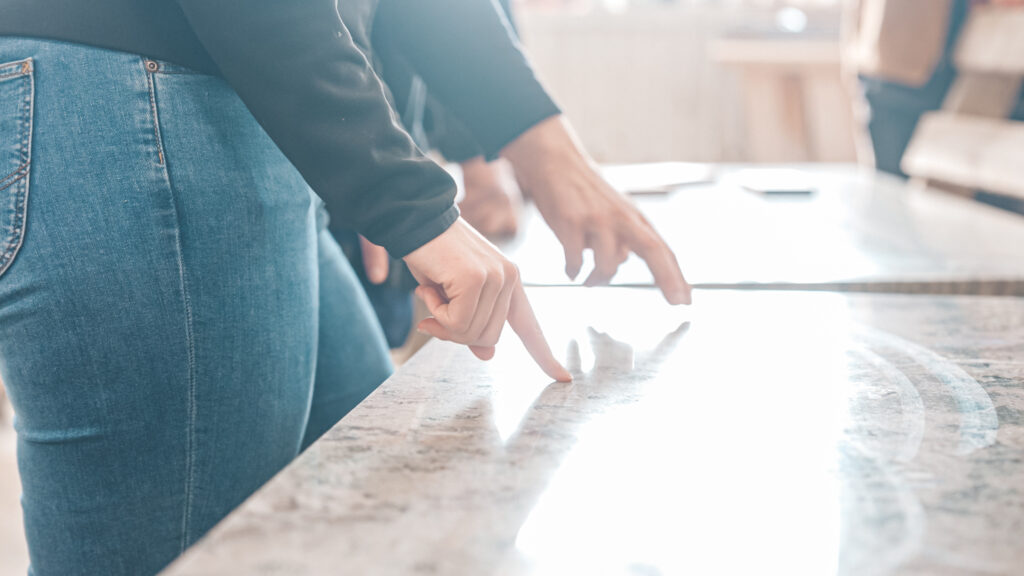 Händer rör en stenskiva av Kolmårdsmarmor